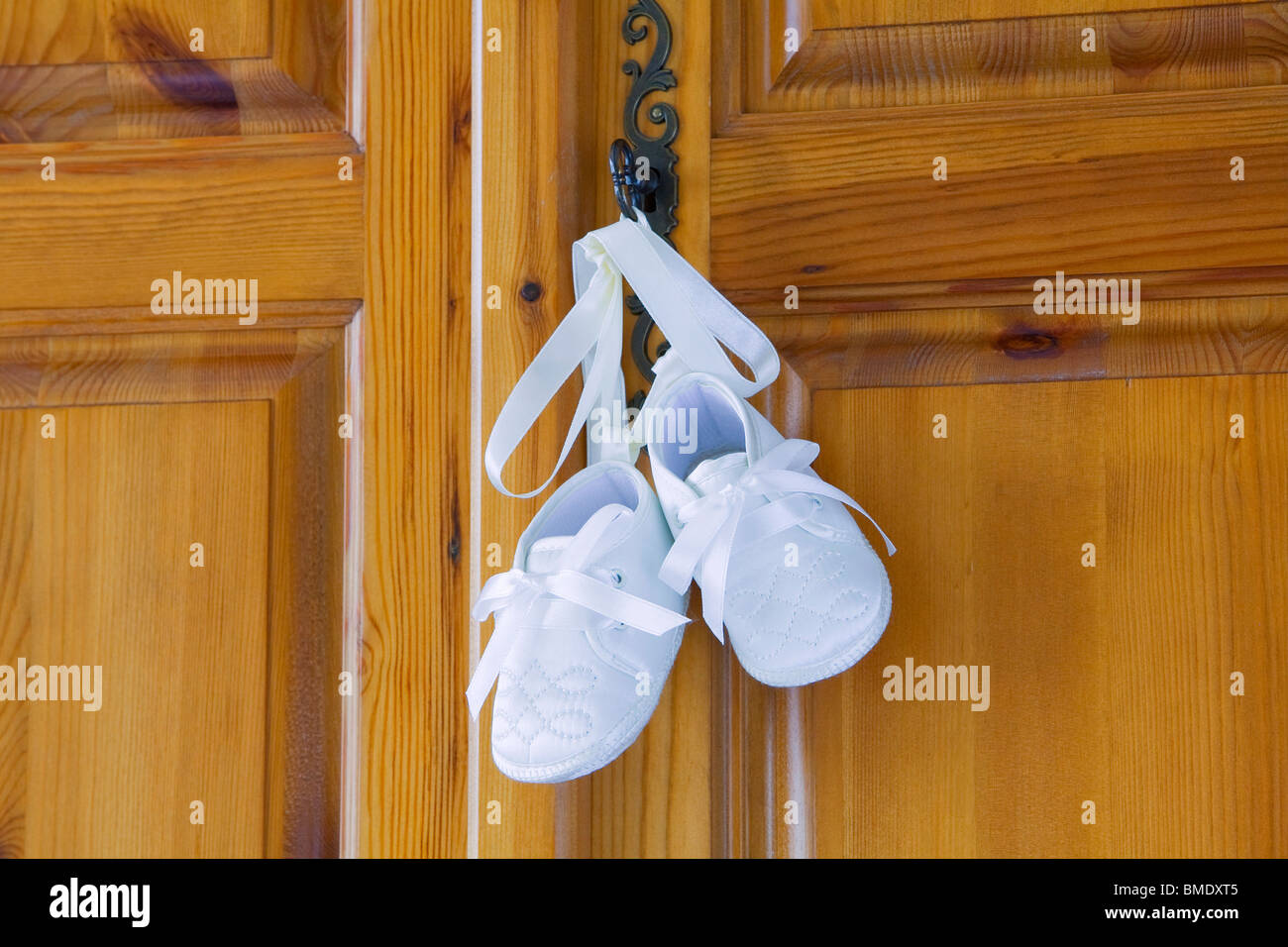 Taufe, Schuhe oder Stiefel für ein Baby zusammengebunden mit Seidenband, von einer Schranktür hängen Stockfoto