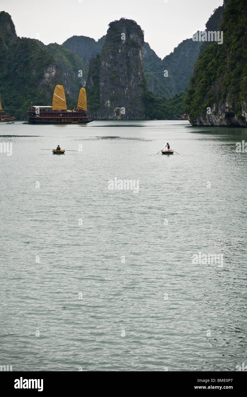 2 Ruderboote nähern ein Junk-Boot voller Touristen auf Halong Bucht, Vietnam Stockfoto