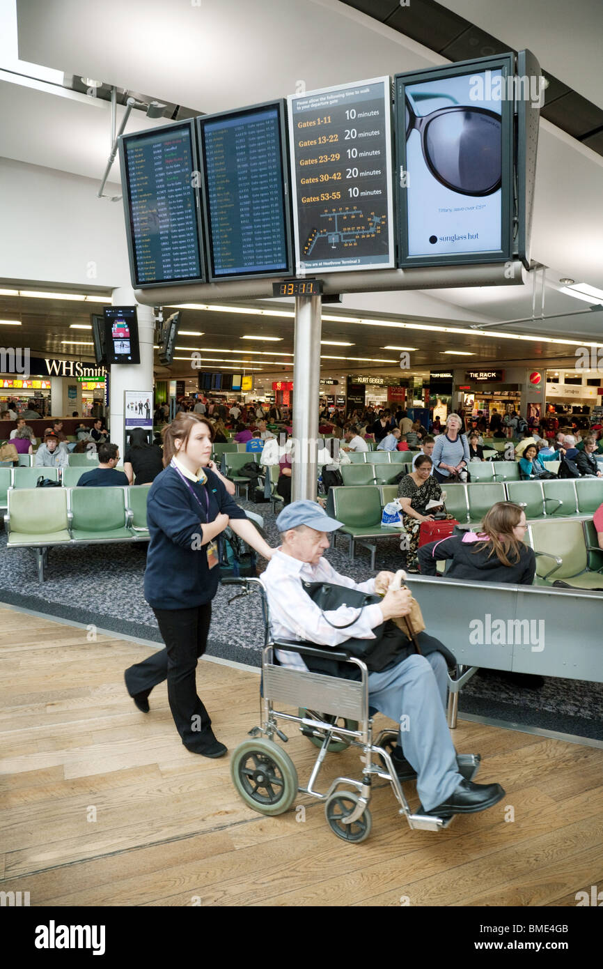 Behinderte Menschen im Rollstuhl ergriffen, um seinen Flug, Abflugbereich von Terminal 3, Flughafen Heathrow, London UK Stockfoto