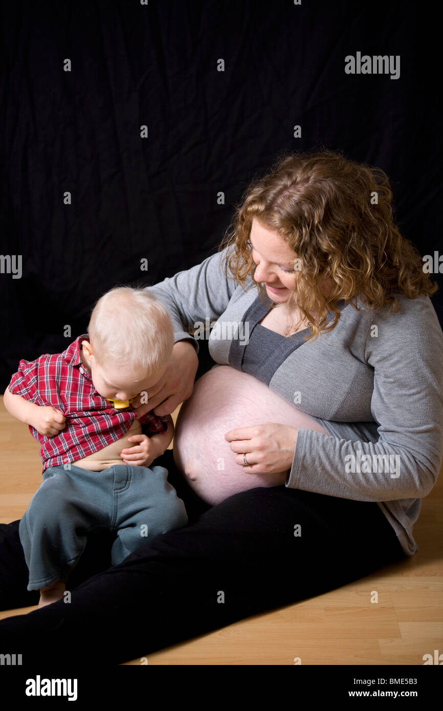 Schwangere Mutter mit 18 Monate alten Sohn Prüfung seinen Bauch. Stockfoto