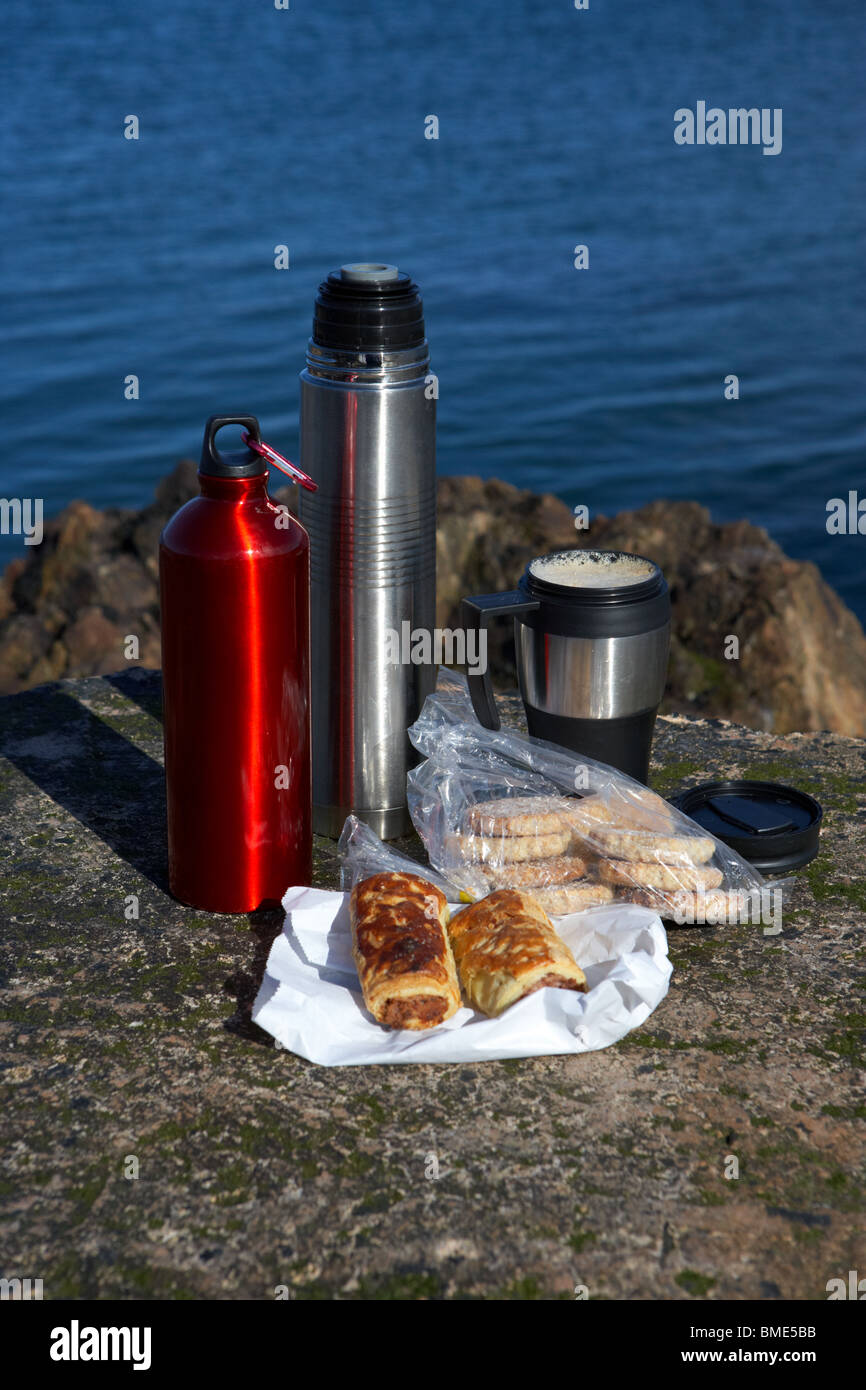 Mittagessen inklusive Wurst Brötchen Kaffee und Kekse Fläschchen auf Felsen auf der Grafschaft Antrim Küste Nord-Irland Stockfoto