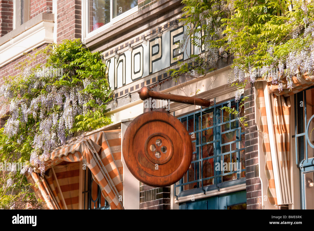 Der Knopenwinkel, Buttonshop, Button Shop, einem berühmten Fachgeschäft an der Herengracht in Amsterdam. Glyzinie im Frühjahr. Stockfoto