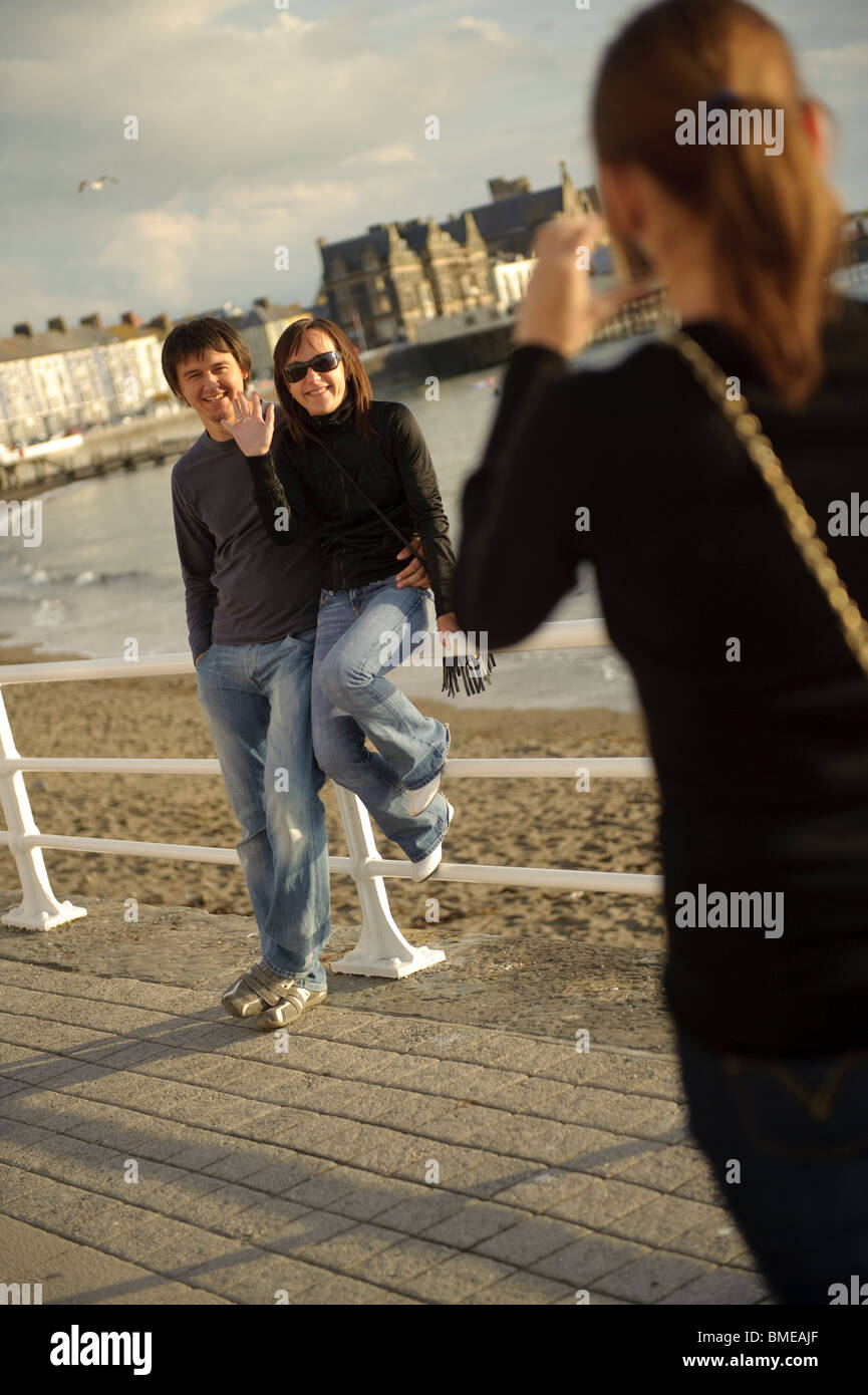 ein junges Paar fotografiert sitzt auf dem Geländer Aberystwyth Promenade, Wales UK Stockfoto