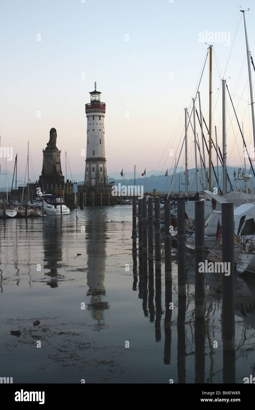 Lindauer Hafeneinfahrt, Yachthafen und Leuchtturm am Bodensee in Deutschland in der Abenddämmerung mit Spiegelungen im Wasser Stockfoto