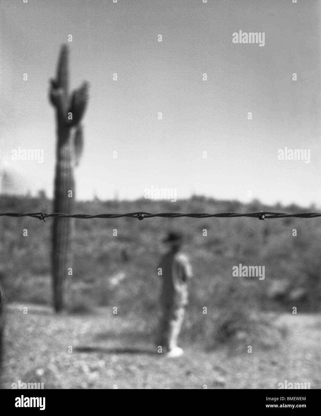 Illegale Einwanderer Person auf der anderen Seite der Grenze Stacheldraht Stockfoto