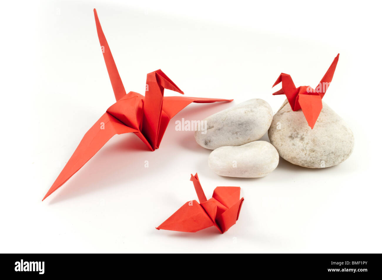 Rot-Origami-Kranich und seinen Kindern auf weißen Steinen Stockfoto
