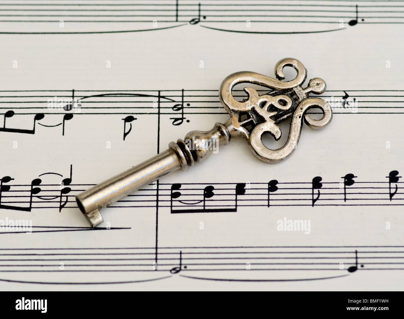 Klavierschlüssel oder alter Skelettschlüssel mit Lire- und Violinschlüssel-Design auf klassischen Noten. Dies ist eine Nahaufnahme, die musikalische Noten zeigt. Stockfoto