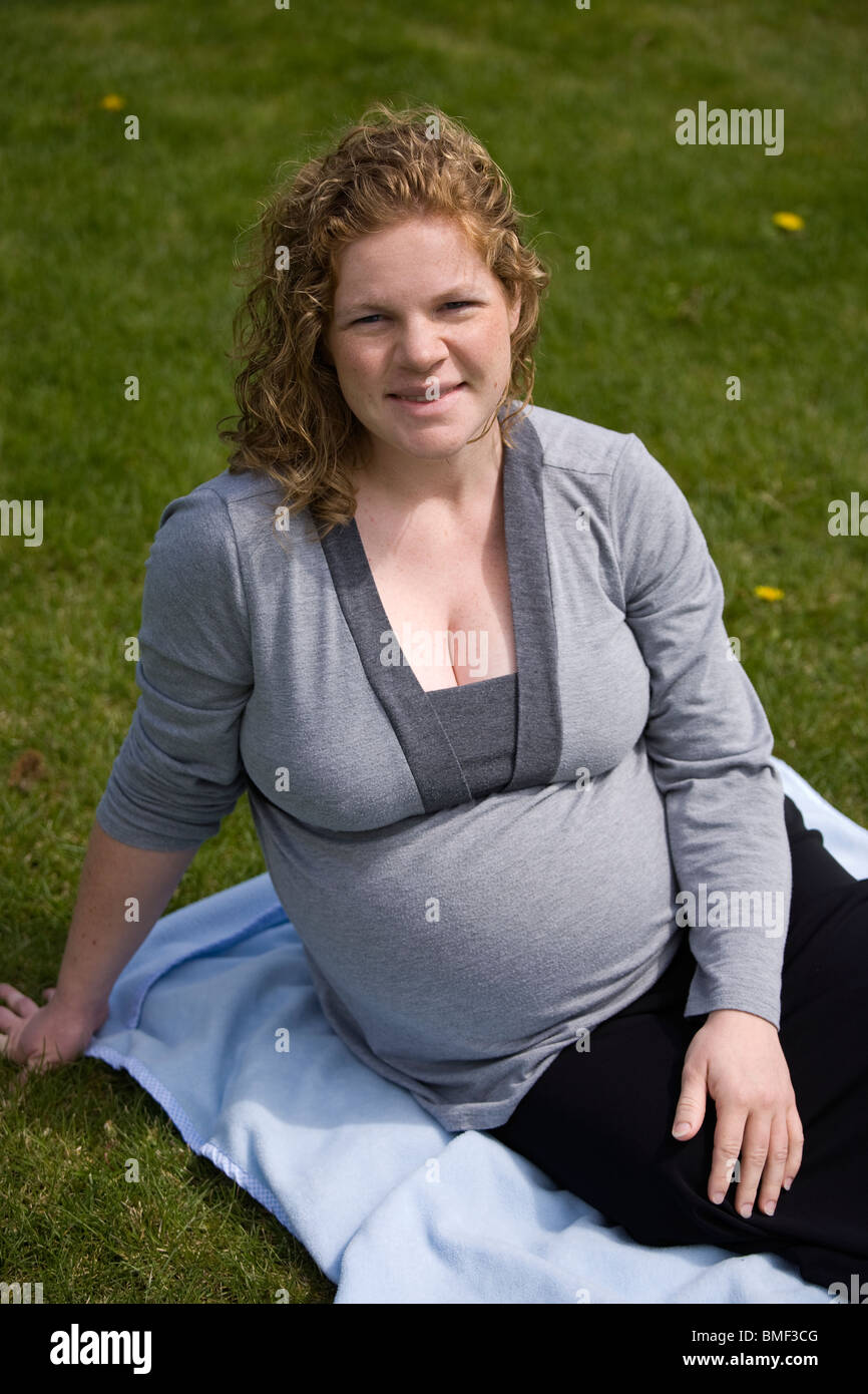 Schwangere Frau, volle Amtszeit, sitzen auf dem Rasen. Stockfoto