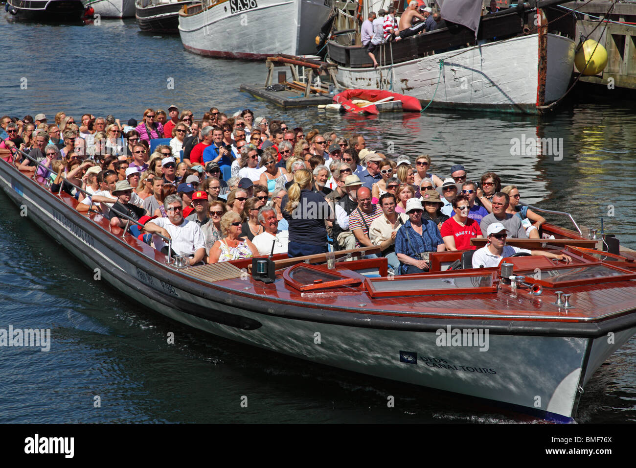 Ein Kanal Tour Kreuzfahrt Schiff voller Touristen im Sommer verlässt Nyhavn auf eine Rundfahrt im Hafen von Kopenhagen. Stockfoto