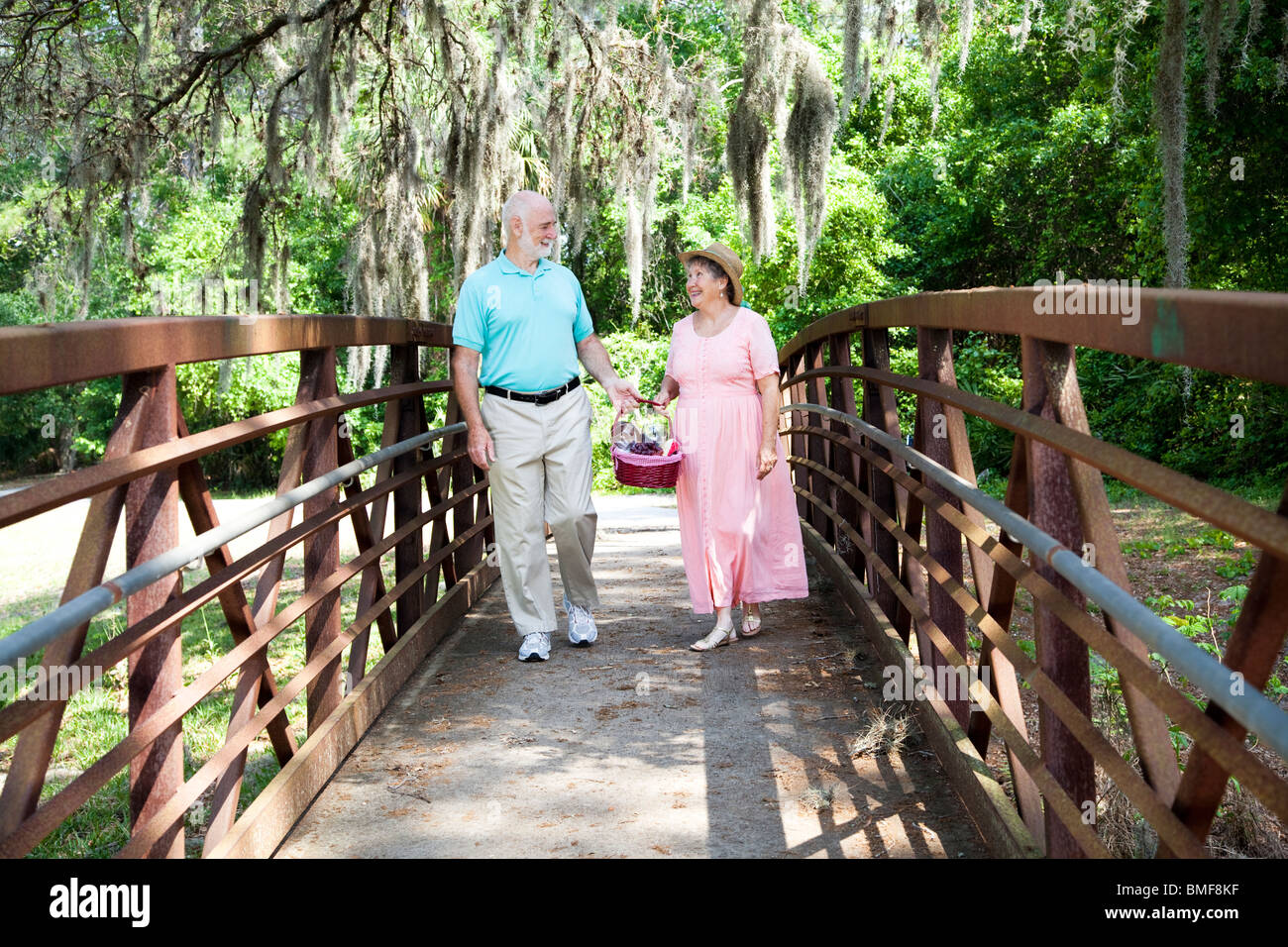 Älteres Paar, ein Spaziergang durch den Park auf dem Weg zu einem Picknick. Stockfoto
