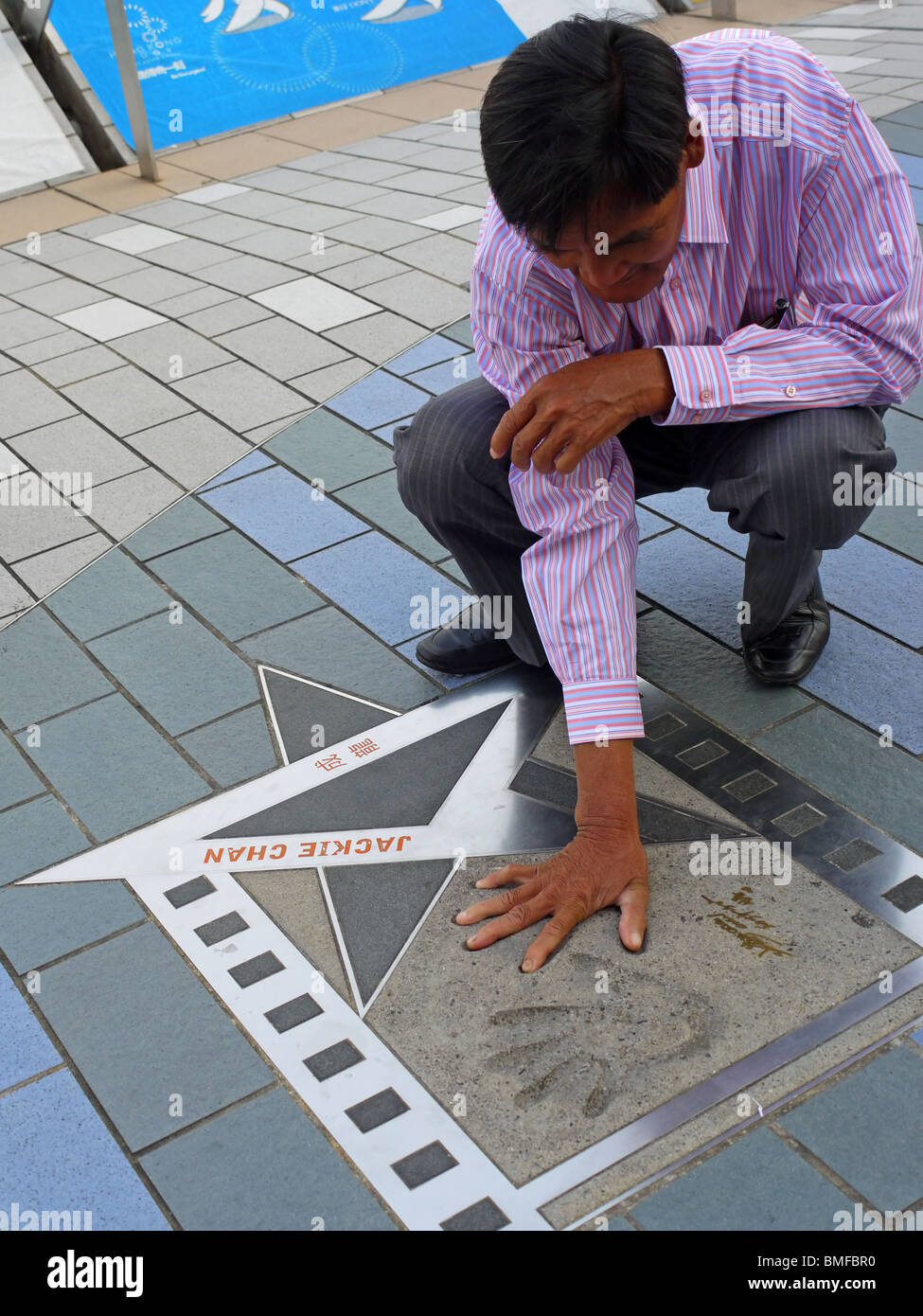 Chinesischer Mann, seine Handfläche auf die Impress von Jackie Chan palm auf der Avenue of Stars in Hongkong, China Stockfoto