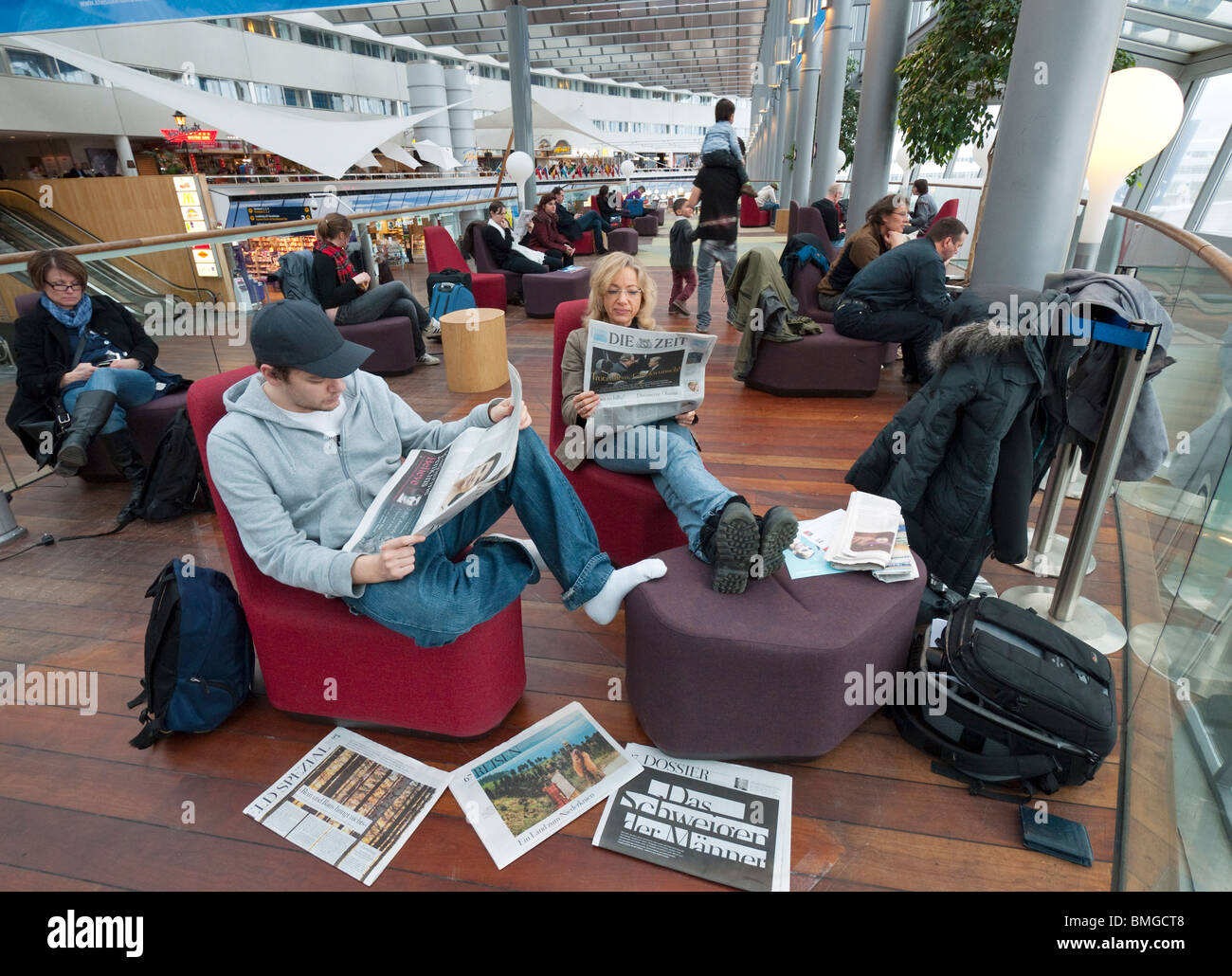 Reisende auf dem Flughafen Stockholm-Arlanda lesen Zeitungen während des Wartens auf ihr Flugzeug. Stockfoto