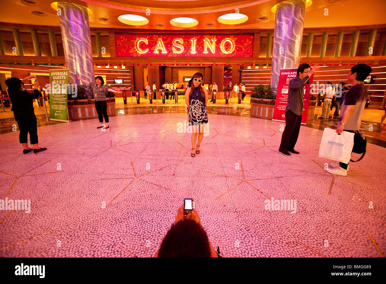 Touristen posieren für Fotos am Eingang des Casino Resorts World Sentosa in Singapur Stockfoto