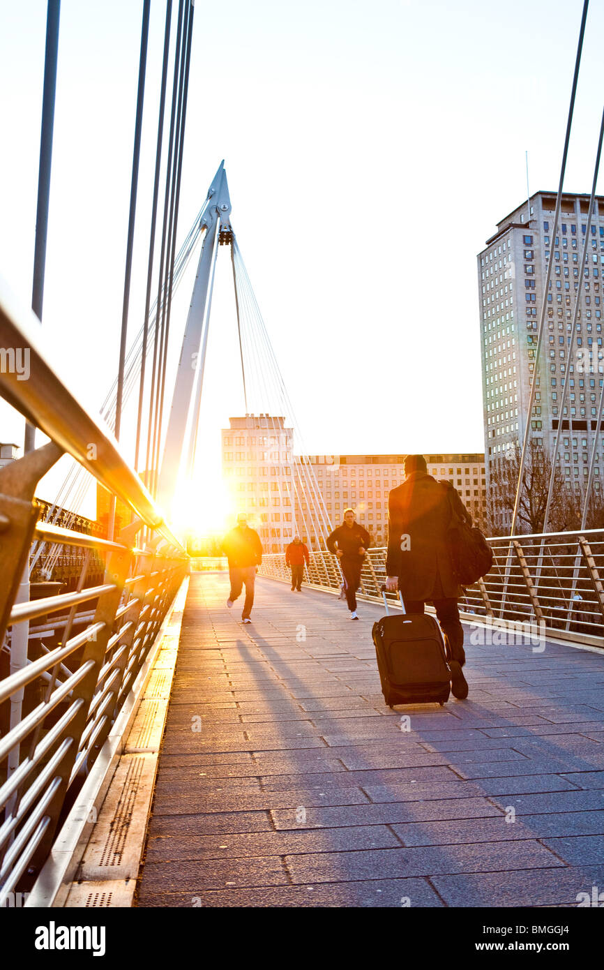 Pendler und Jogger auf Hungerford Bridge überqueren Sie die Themse in frühen Morgensonne Stockfoto