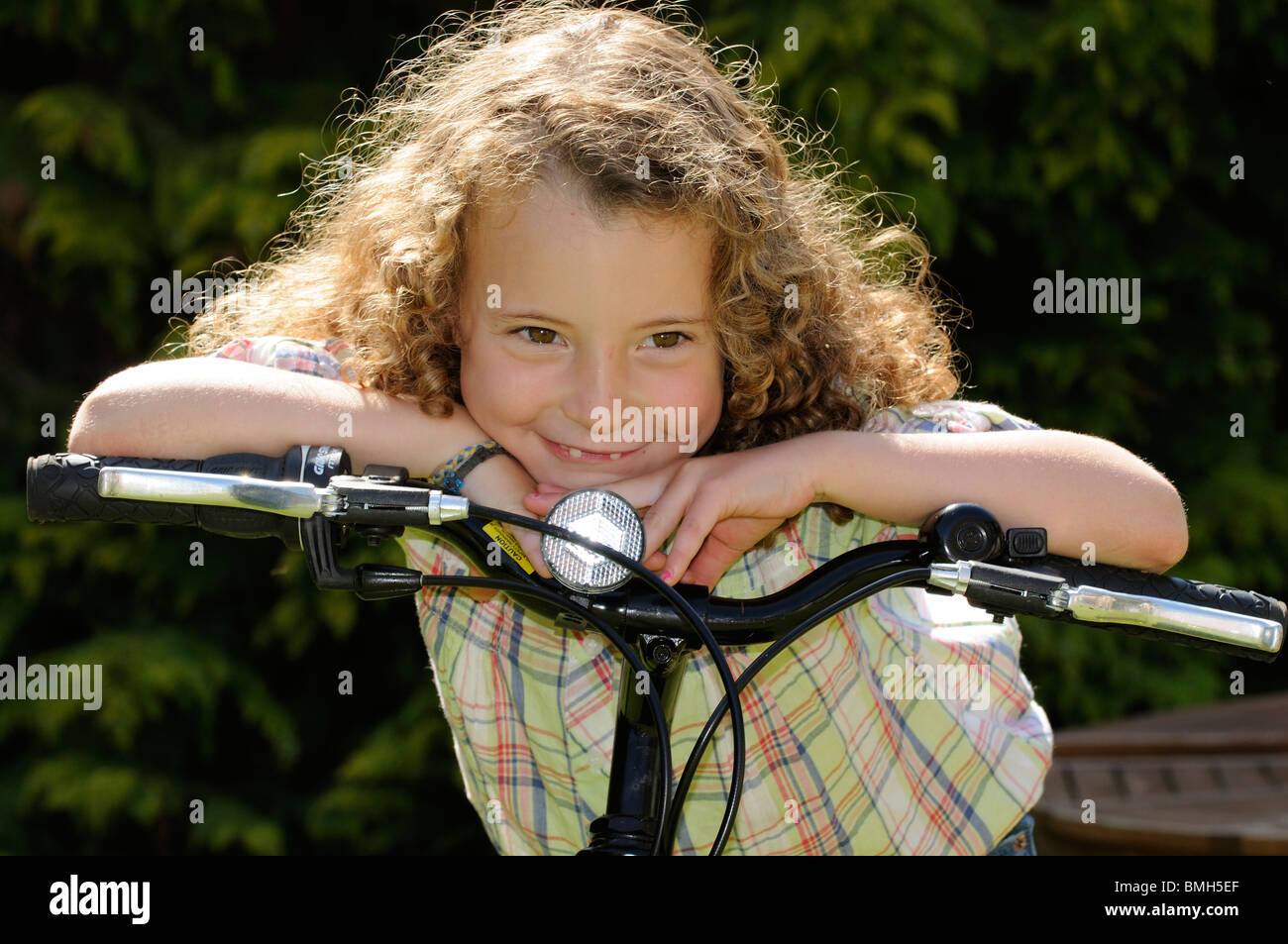 Porträt eines Mädchens stützte sich auf den Lenker ihres Fahrrads hat sie ihre vorderen Zähne fehlen Stockfoto