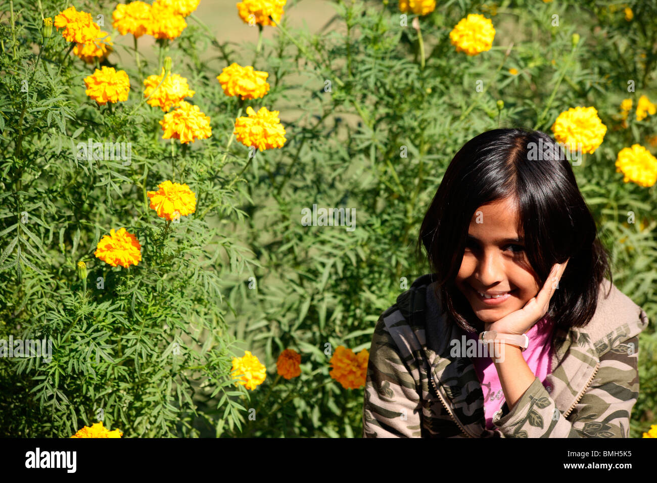 Eine junge Inderin lächelnd in einem Garten Stockfoto