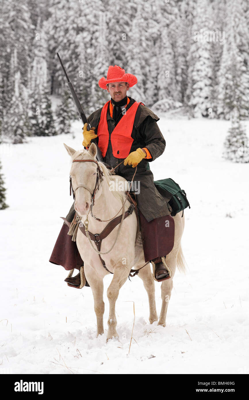 Cowboy Jäger weiß Reitpferd im Schnee mit Gewehr Jagd Stockfoto