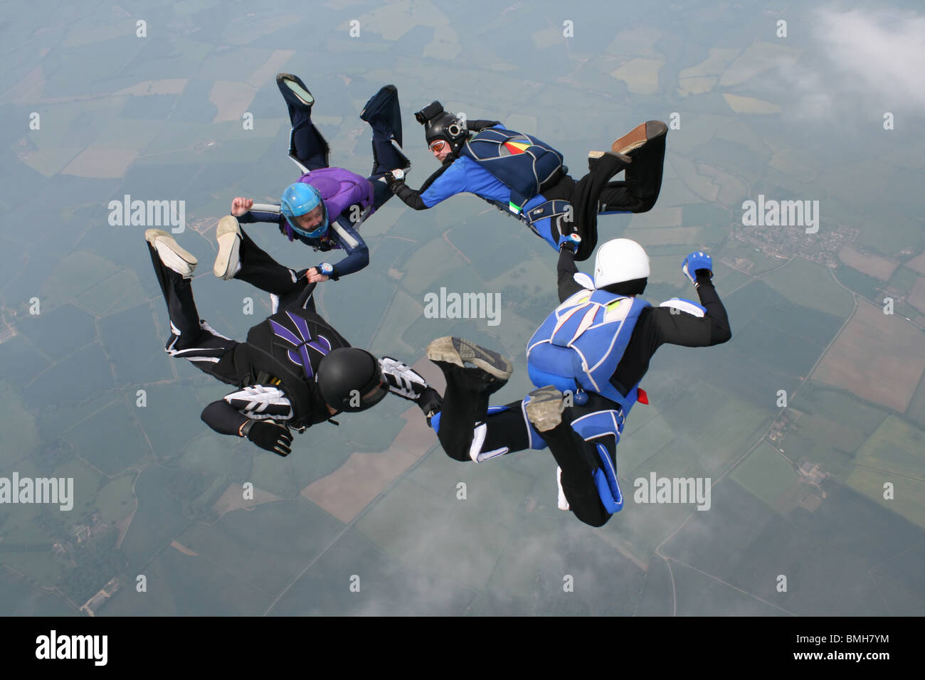 Vier Fallschirmspringer bilden einen Kreis, während im freien Fall Stockfoto