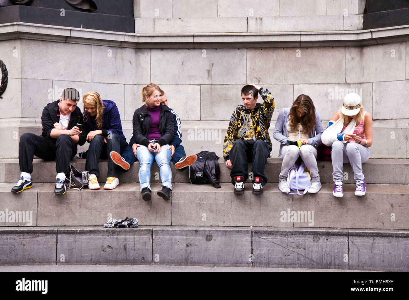 Irische Jugendliche sitzen auf Basis der O'Connell Statue in der Stadt Stockfoto