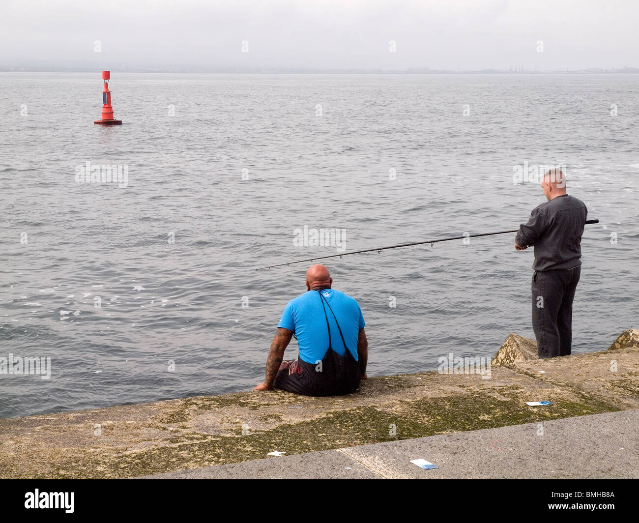 Zwei Männer Makrelen angeln am Ende des South Gare Wellenbrecher am Teesport Stockfoto