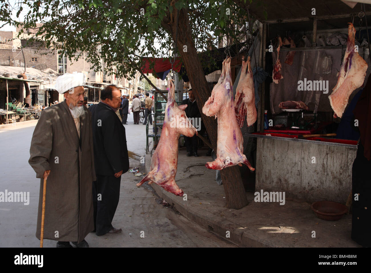 Kunden, die Inspektion Kadaver auf einer Straßenseite Metzger in Kashgar, westliche Xinjiang-Provinz, China. Stockfoto