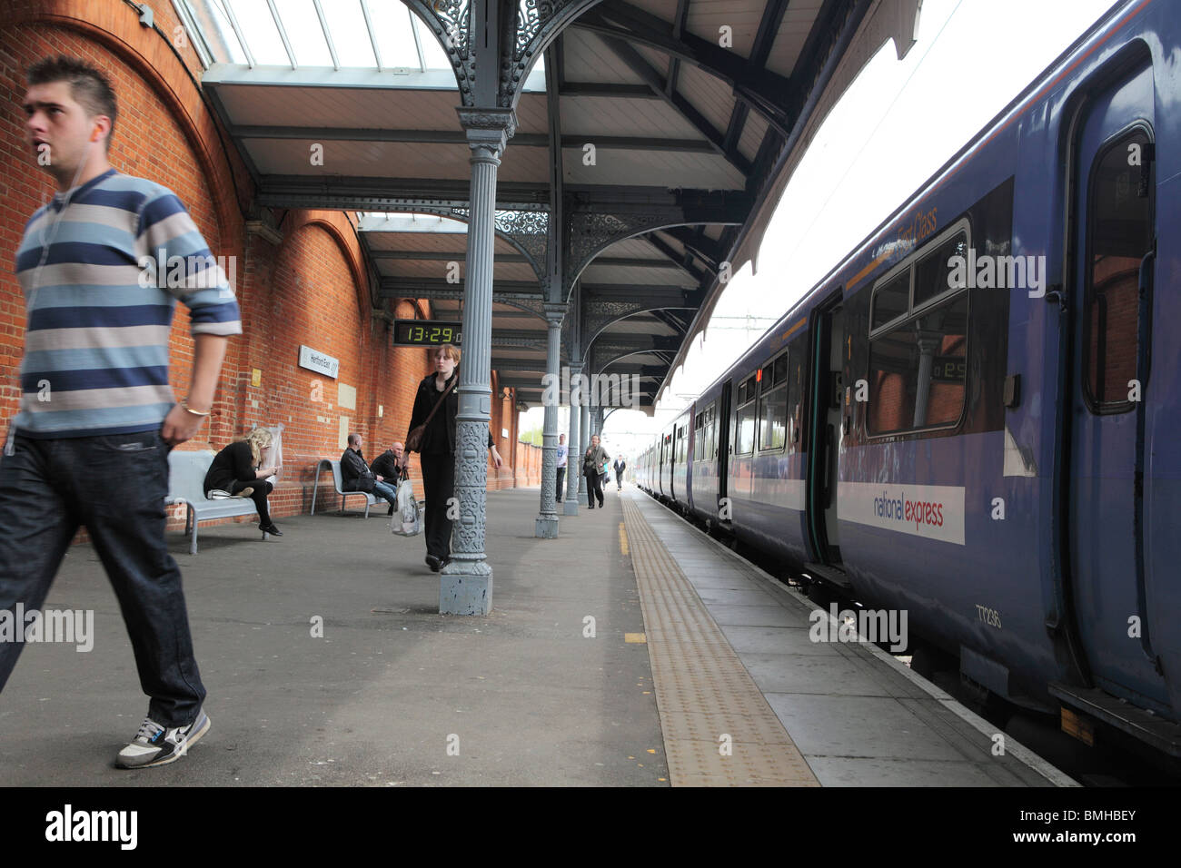 eine traditionelle Bahnhof mit dem Zug in einer Hertfordshire Stadt mit einem Mann zu Fuß einen Zug zu erhalten Stockfoto