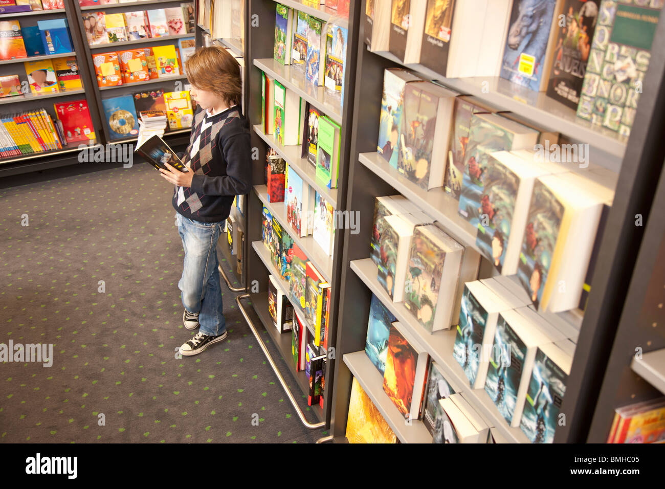 Junge gelehnt Bücherregal lesen Stockfoto