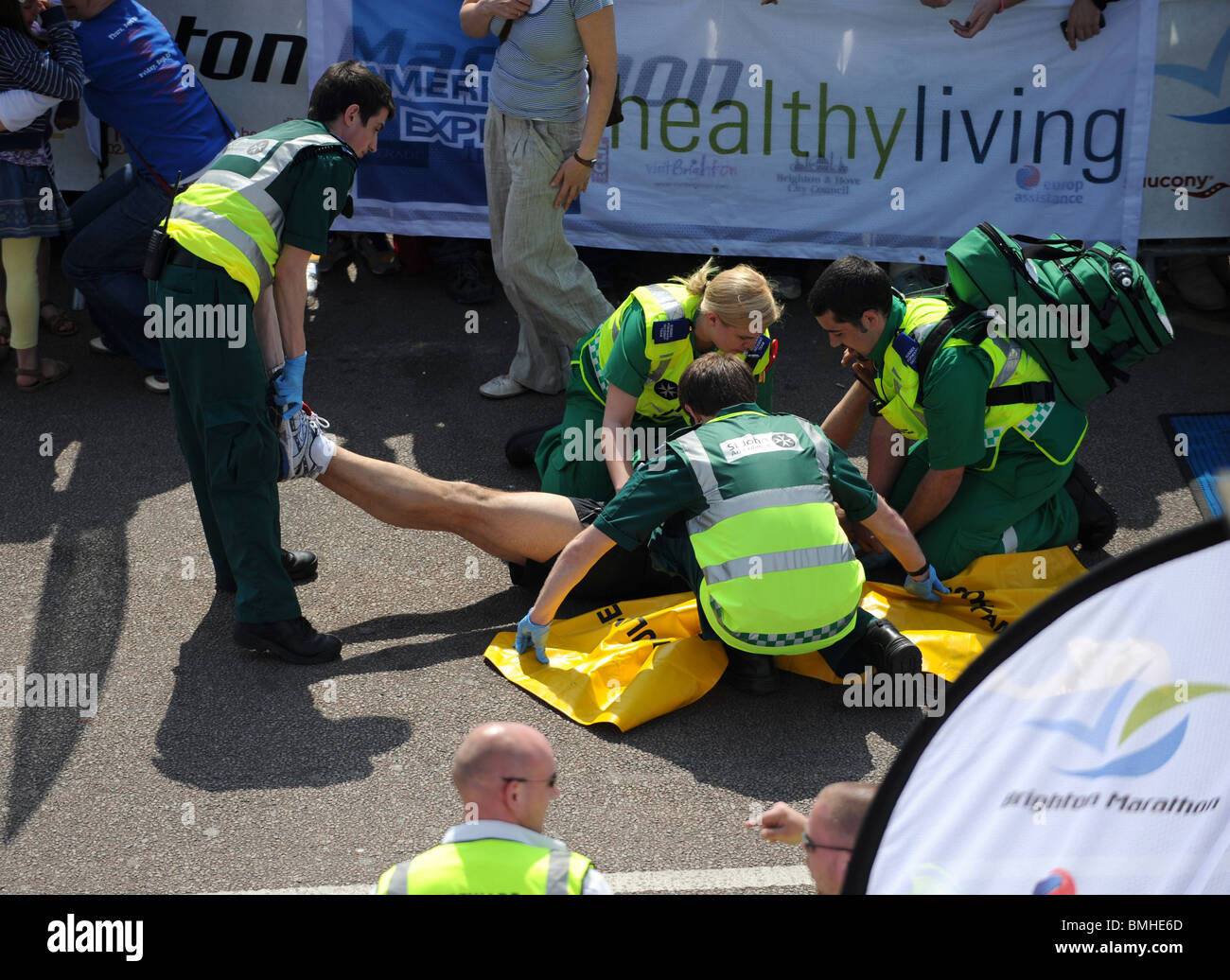 Sanitäter aus St John Ambulance helfen einen Läufer, der am Ende des ersten Brighton Marathon 2010 zusammengebrochen Stockfoto