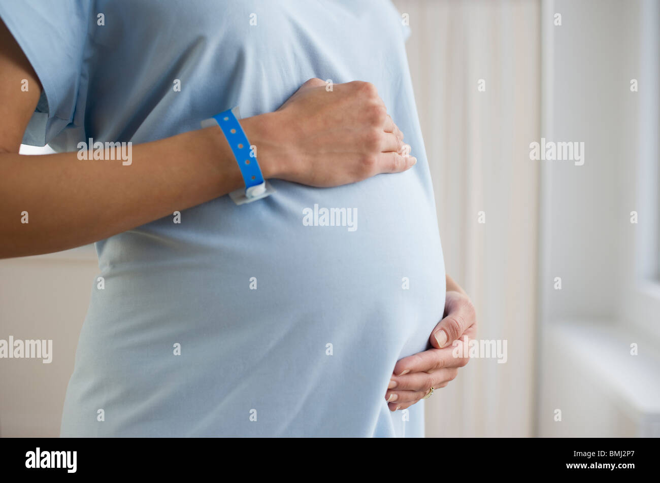 Schwangere Frau tragen Krankenhemd Stockfoto