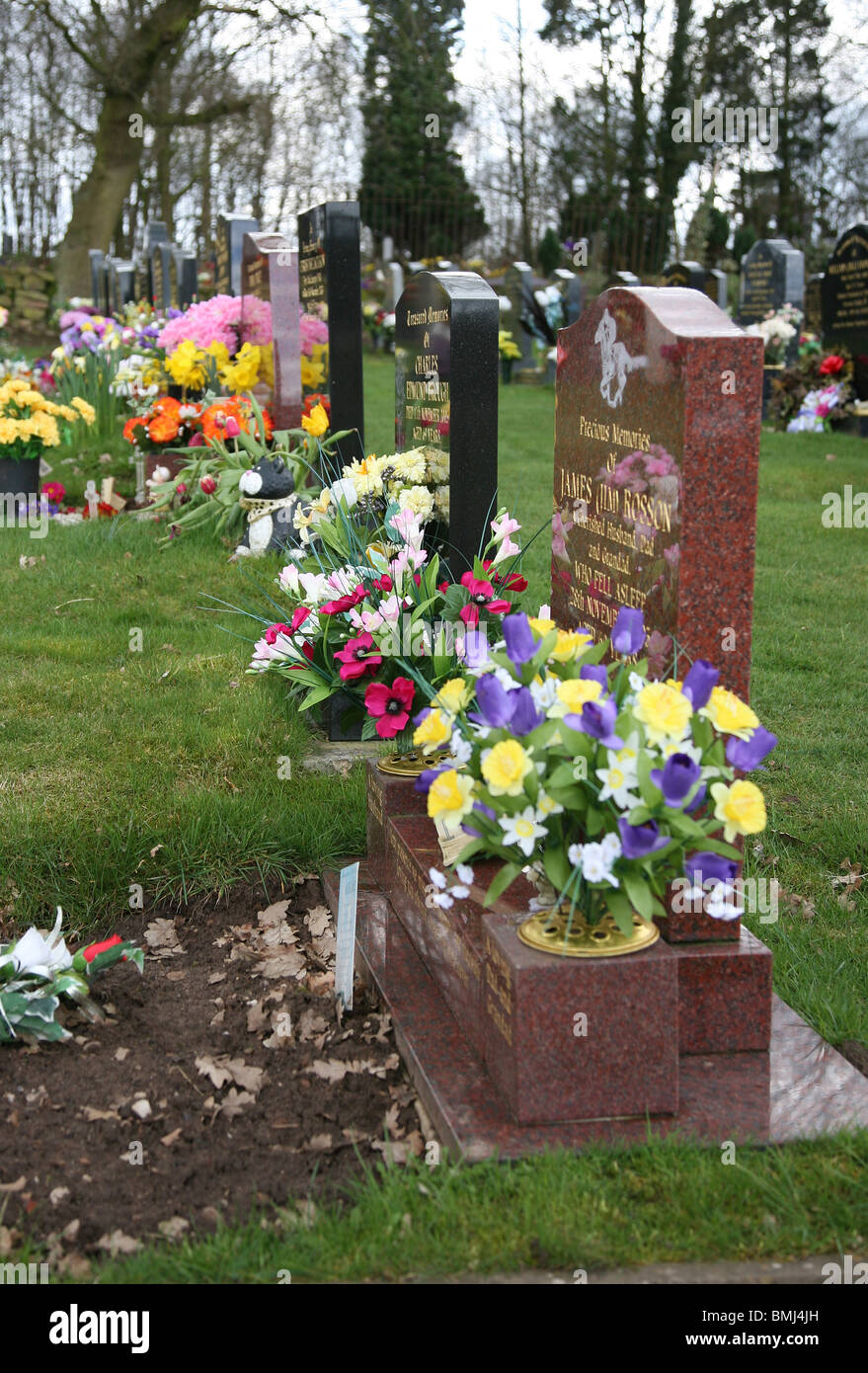 Grabsteine auf einem Friedhof mit Blumen Stockfoto