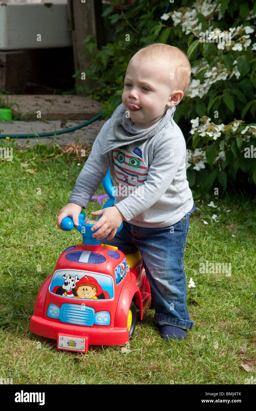 Niedliche Baby junge 13 Monate alt, spielen im Freien auf ein Spielzeug LKW, Hampshire, England. Stockfoto