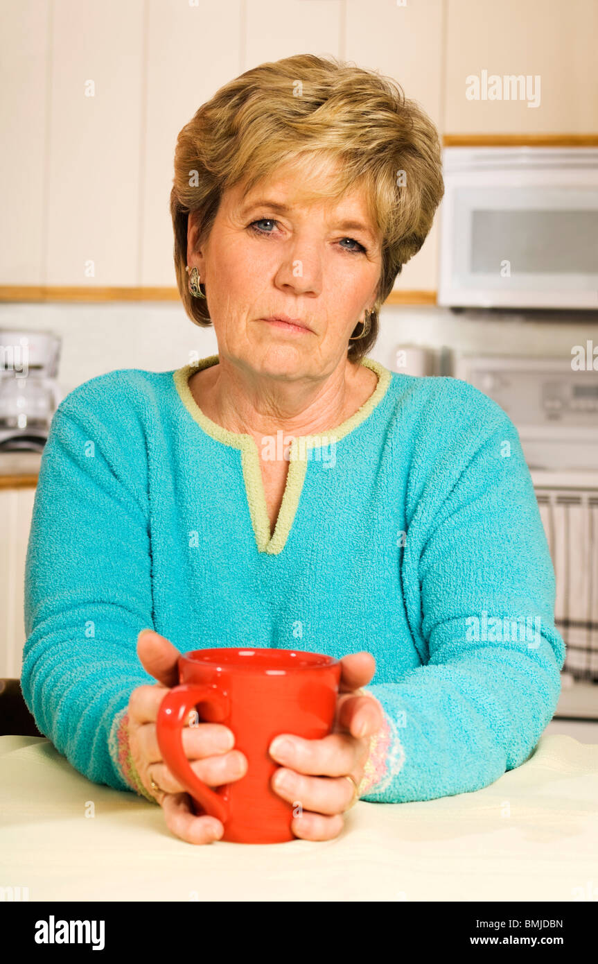 Ältere Frau hält eine Kaffeetasse suchen unglücklich. Stockfoto