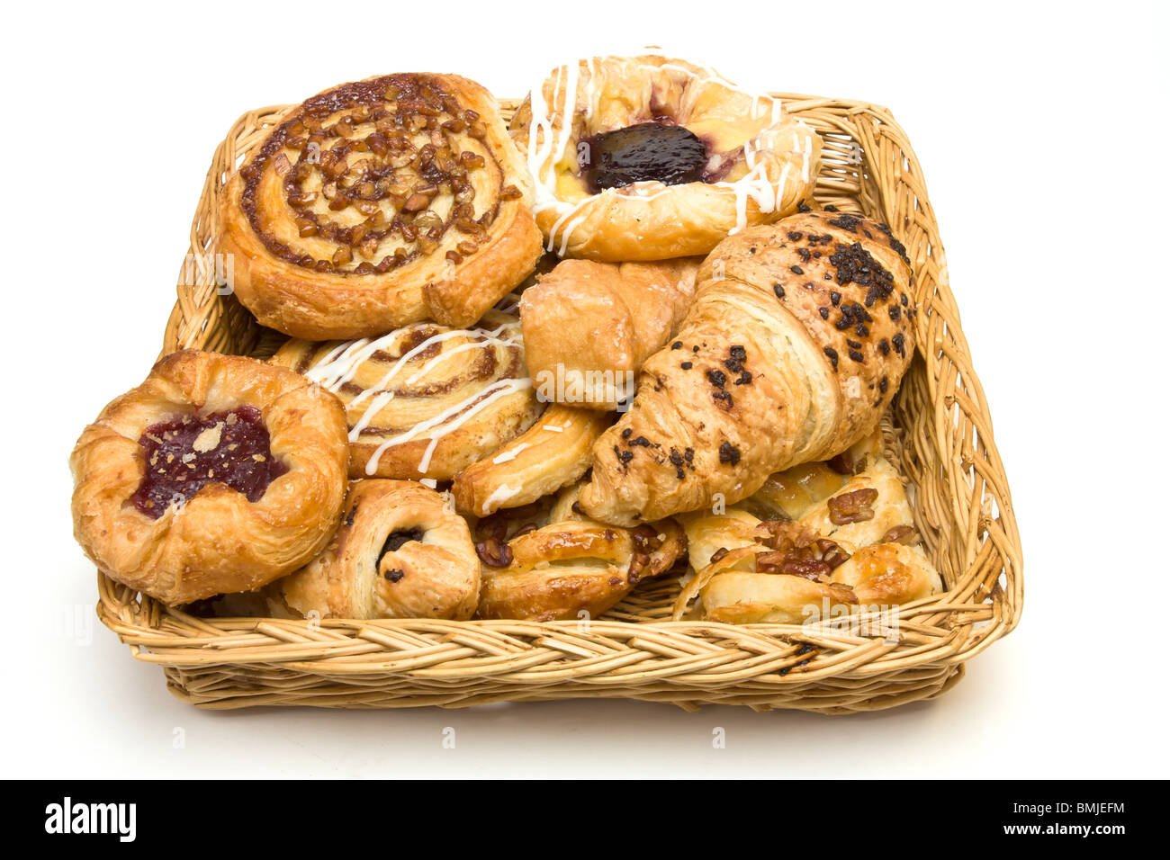 Weidenkorb mit Auswahl an französischen & dänische Gebäck auf weißem Hintergrund. Stockfoto