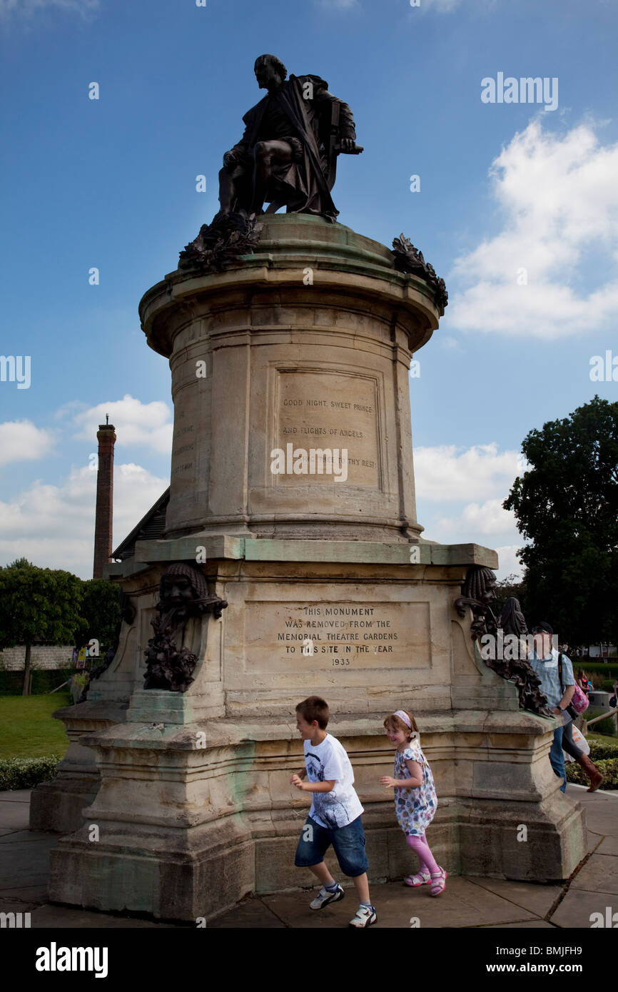 Zwei Kinder spielen neben der Statue von William Shakespeare in dem Hauptpark in Stratford-upon-Avon. Stockfoto