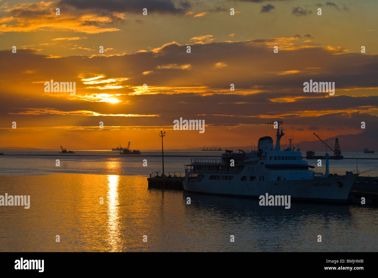 Die Sonne versinkt hinter Schiffe und ein Dock in der Bucht von MANILA - MANILA, Philippinen Stockfoto
