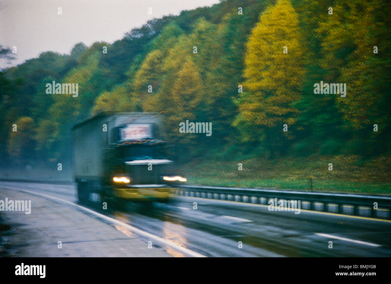 Große industrielle LKW Geschwindigkeiten entlang feuchte Regenzeit fallen Herbst Straße Szene Stockfoto