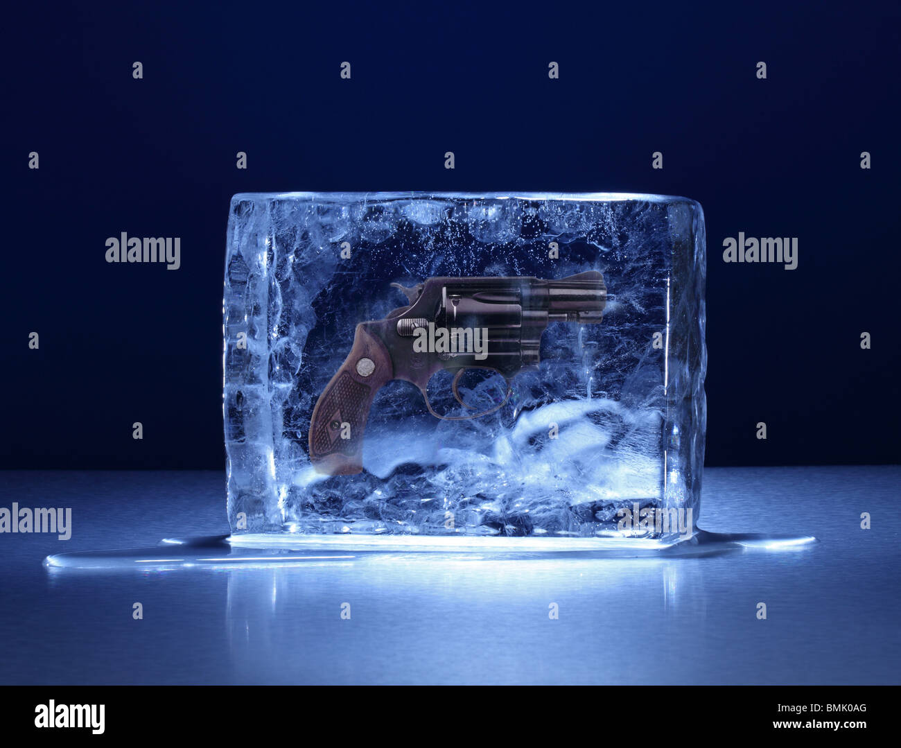 Einen gefrorenen Eisblock mit einer Handfeuerwaffe eingefroren im Inneren auf einer Metalloberfläche Stockfoto