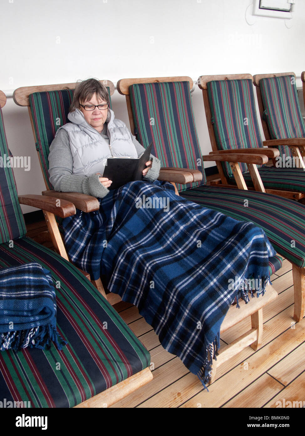 Frau Buch auf dem Liegestuhl. Alaska-Kreuzfahrt Stockfoto