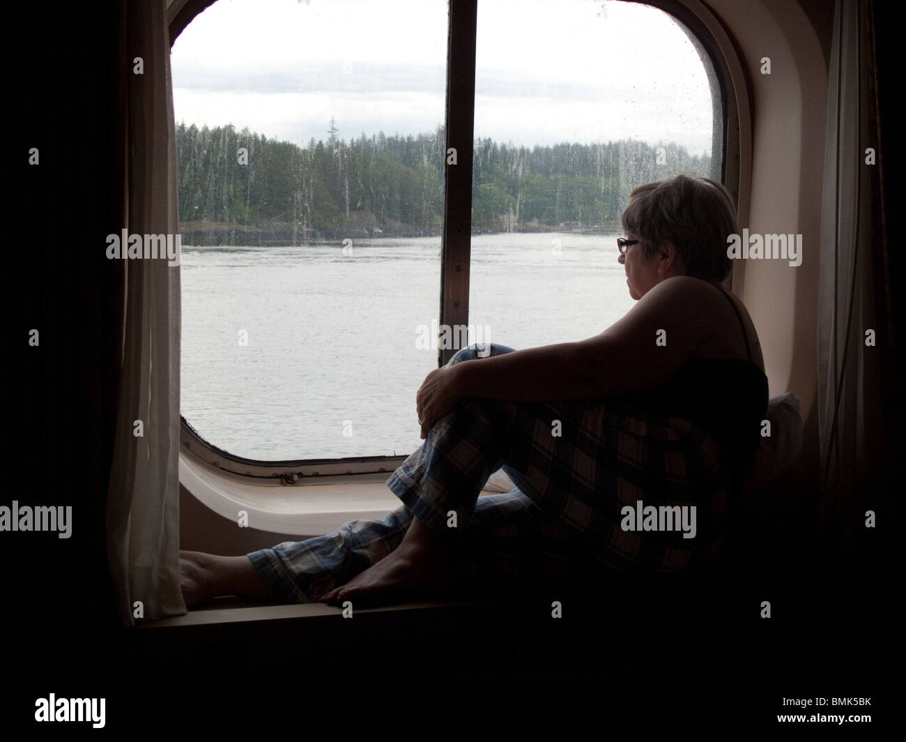 Frau suchen Fenster auf einem Kreuzfahrtschiff. Alaska-Kreuzfahrt Stockfoto