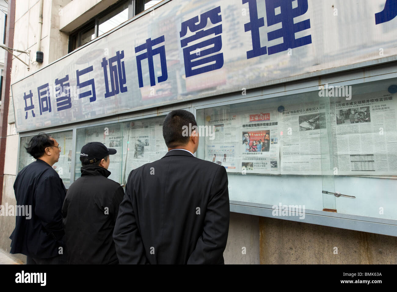 Leute lesen die Shanghai Daily News in Vitrine auf Nanjing Road East, Shanghai, China Stockfoto