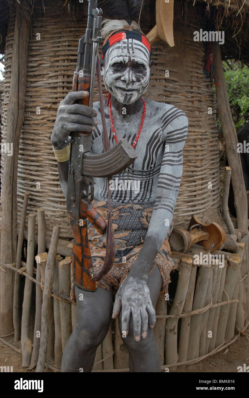 Äthiopien unteren Omo River Basin Chelete ein Duss Stammes-Gemeinschaft Mensch mit Körper und Gesicht Farbe hält AK 47 vor Getreidespeicher Stockfoto