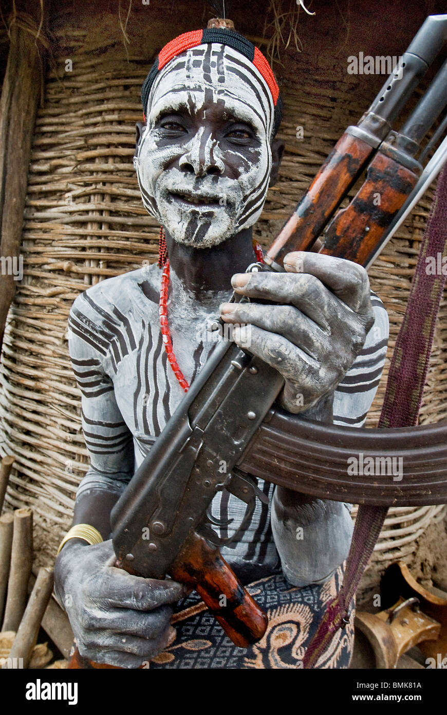 Äthiopien unteren Omo River Basin Chelete ein Duss Stammes-Gemeinschaft Mensch mit Körper und Gesicht Farbe hält AK 47 vor Getreidespeicher Stockfoto
