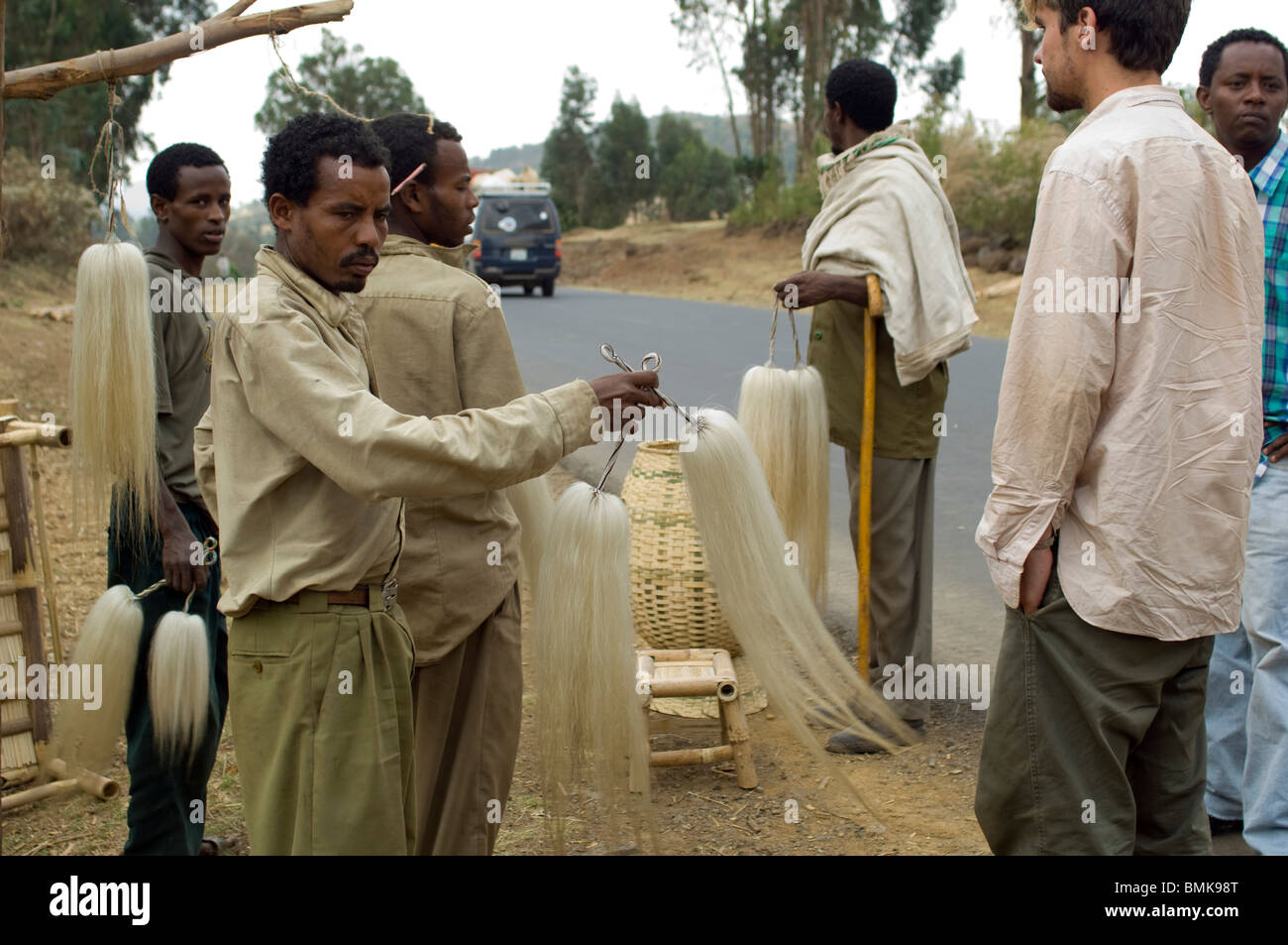 Ein Tourist verhandelt mit lokalen Anbietern, eine Fliegenklatsche, lokale Pferd Schweif, am Highway 3, in der Nähe der Stadt Bure, Äthiopien zu kaufen. Stockfoto