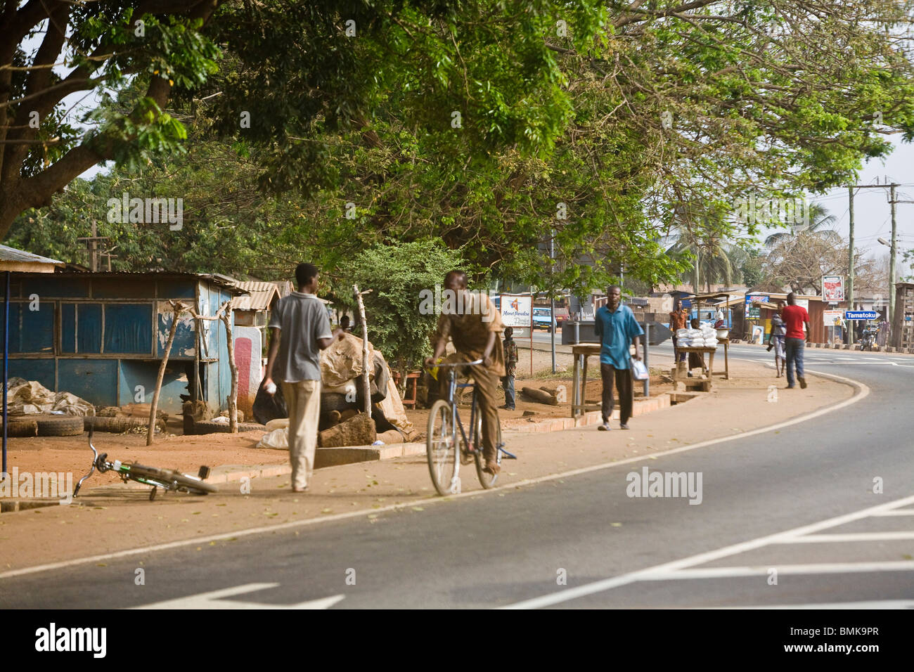 Afrika, Westafrika, Ghana, Küstenstraße. Männer wandern und Radfahren, viel befahrenen Straße. Stockfoto