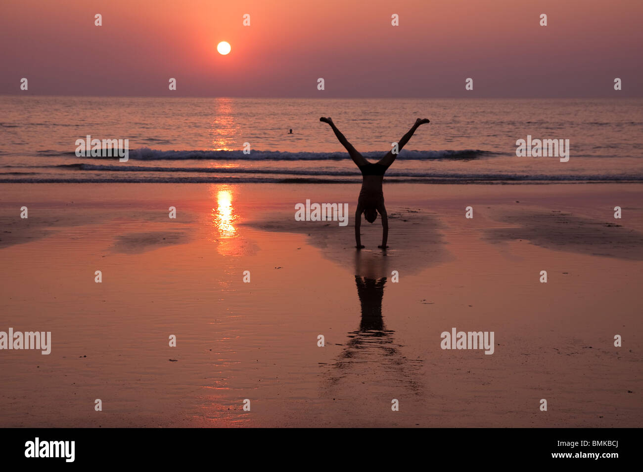 Mann macht einen Handstand dabei Yoga am Strand von Kudle, Gokarna Stockfoto