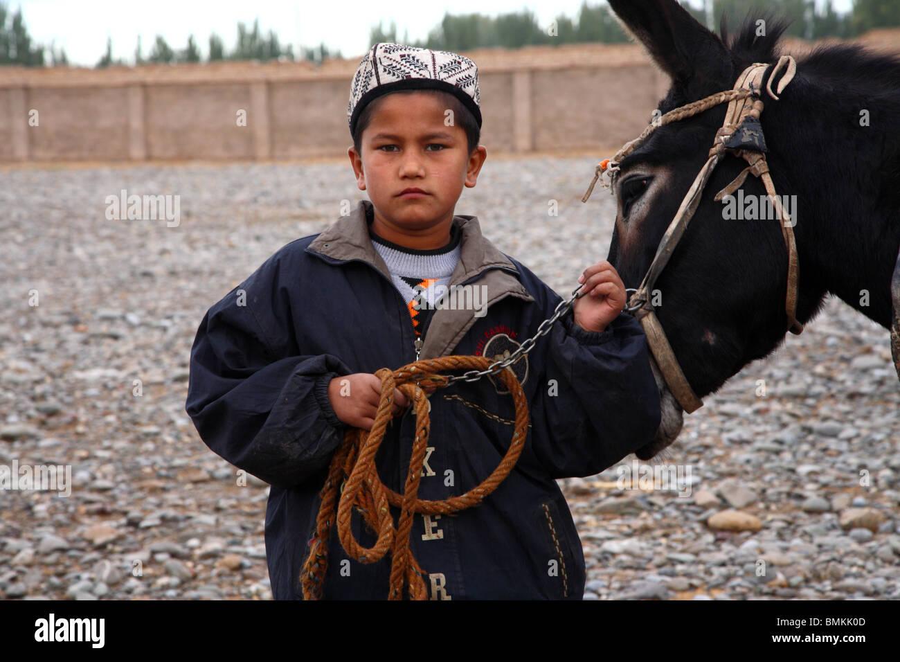 Junge die Zügel von seinem Esel auf dem Bauernmarkt Kashgar in Kashgar, westliche Xinjiang Provinz, VR China. Stockfoto