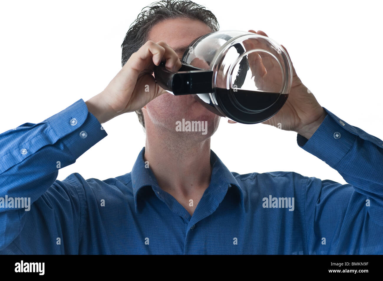Ein Mann in einem blauen Kleid Shirt, trinken aus einer Kaffeekanne, isoliert auf weiss. Stockfoto