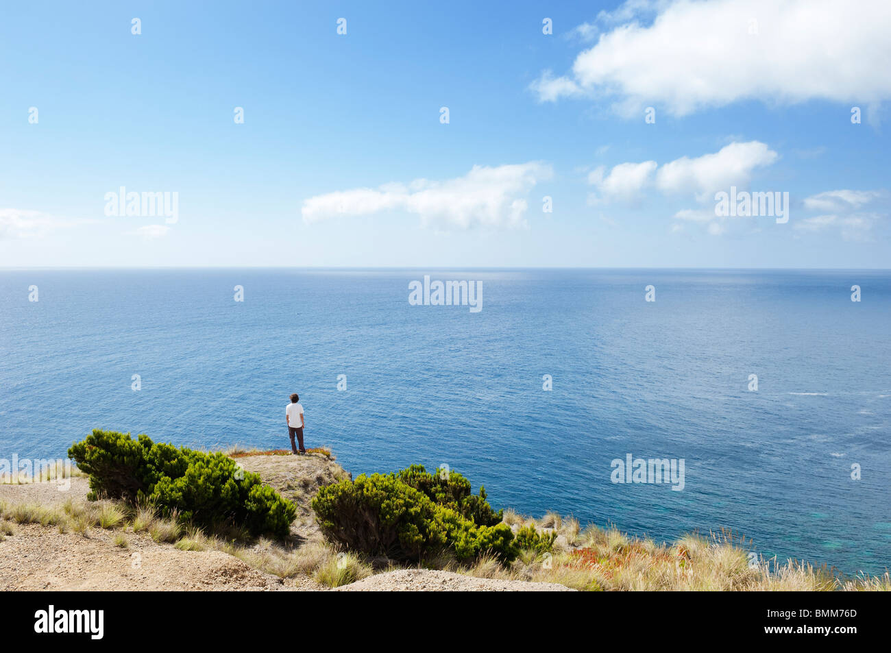 Mann am Rand einer Klippe auf der Suche auf See in Insel Faial, Azoren, Portugal Stockfoto