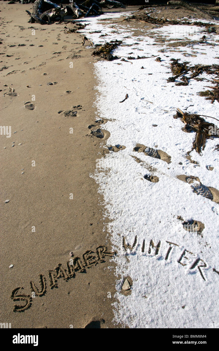 Sommer und Winter Worte geschrieben in Sand und Schnee am Strand, Devon, UK Stockfoto