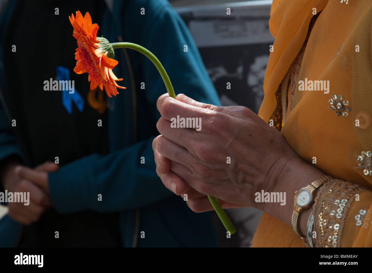 Orange Blume in der Hand der Sikh Frau wartet, um sie in Hommage an Toten in 1984 indischen Massakern zu legen.  London, UK. 13.06.2010 Stockfoto